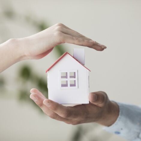 close-up-hands-protecting-small-house-model_23-2148204008